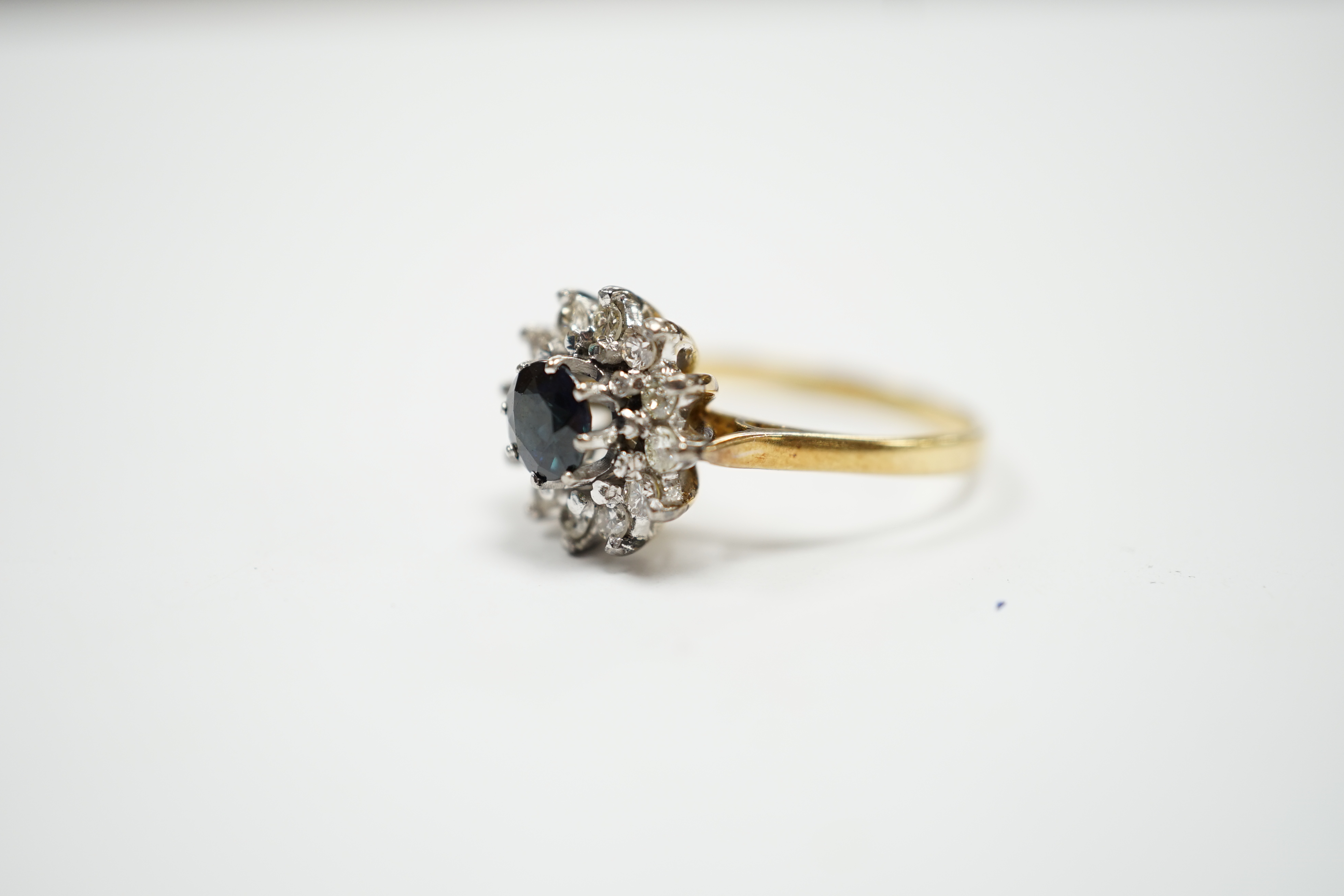 An 18ct, sapphire and diamond set circular cluster ring, size N, gross weight 3.9 grams.